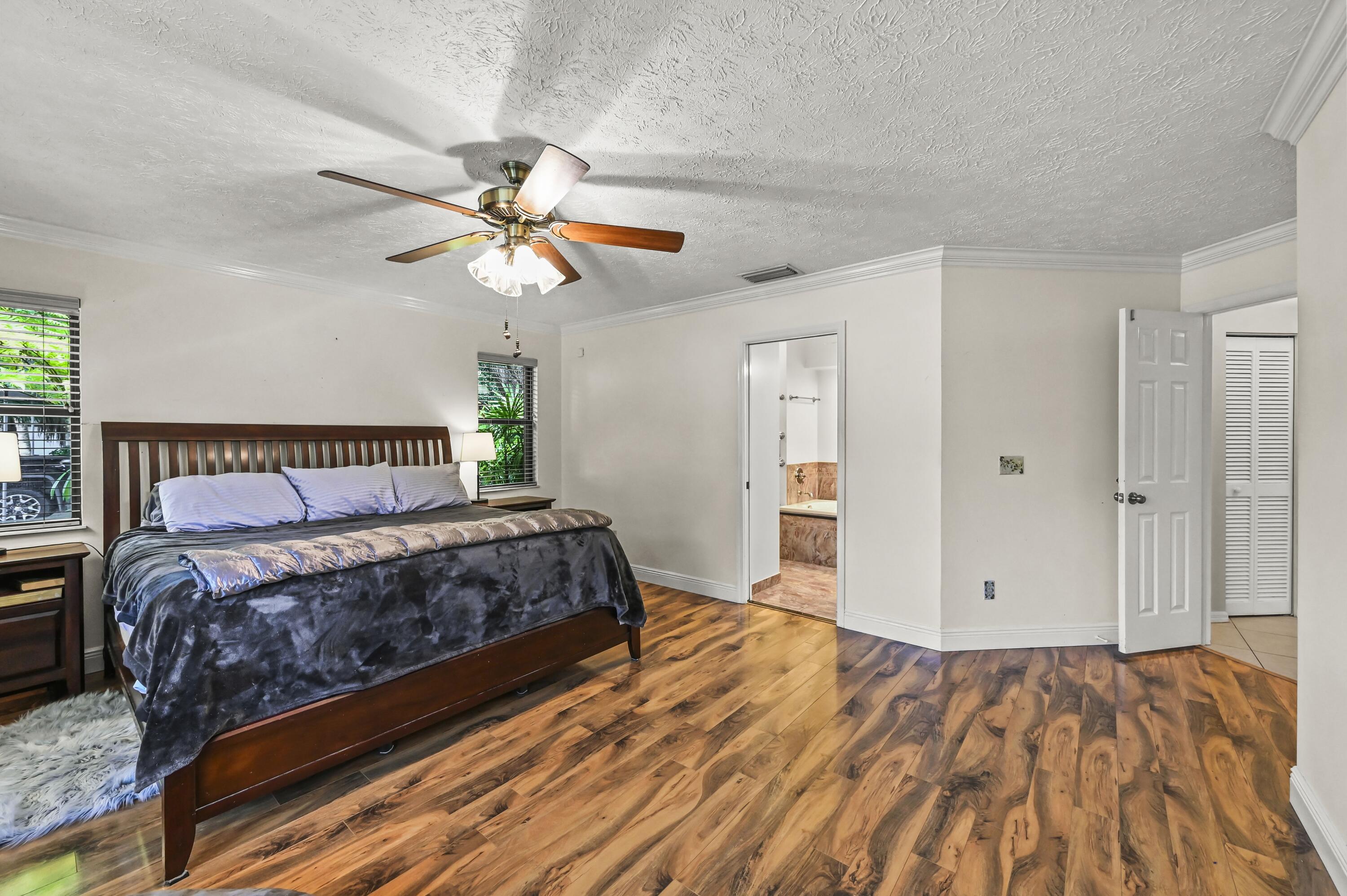 Furnished bedroom with wood-look floors, a dark wood bed, and an adjoining bathroom.