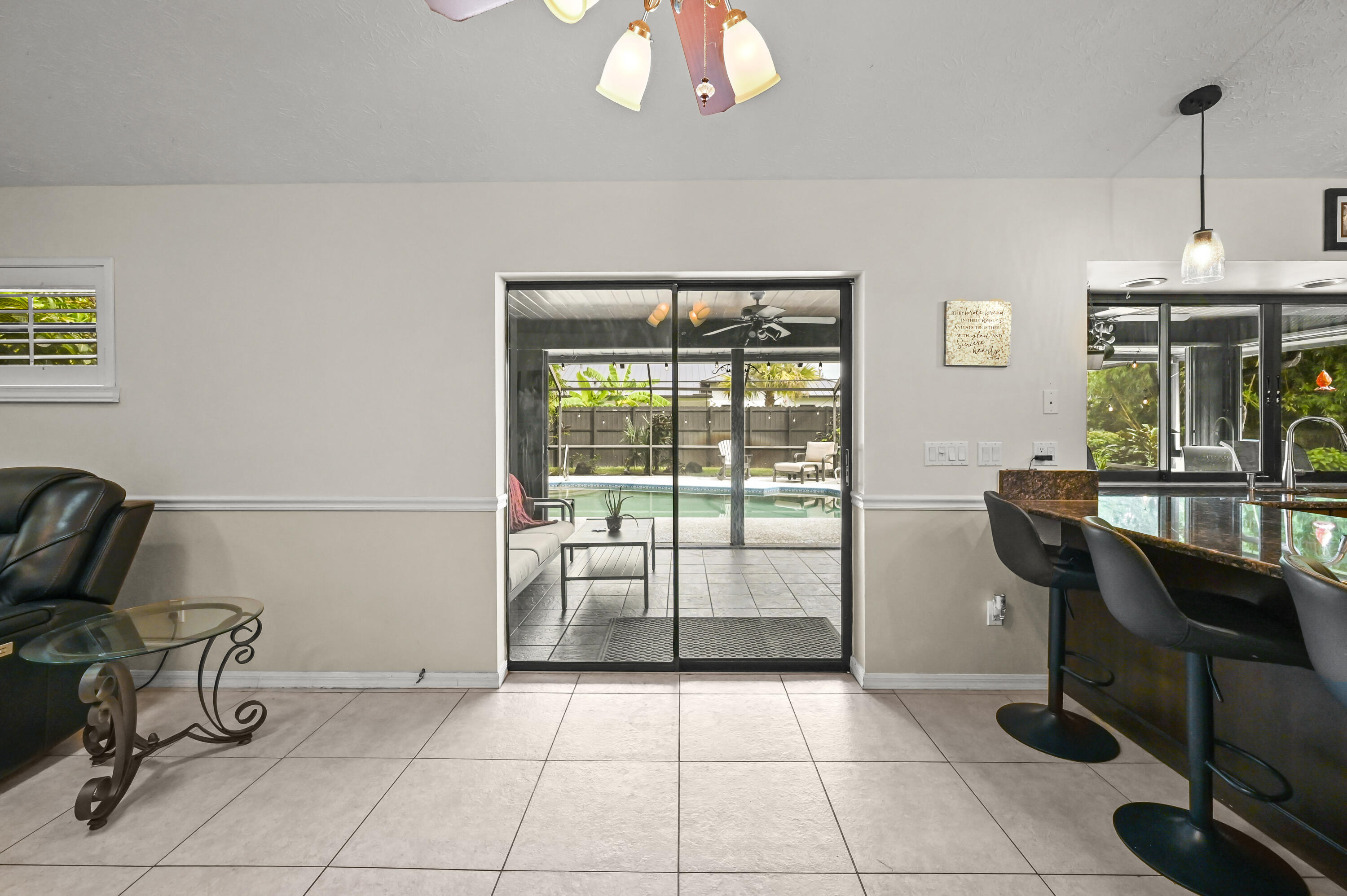 Living and dining area with a breakfast bar and sliding doors overlooking a backyard pool.