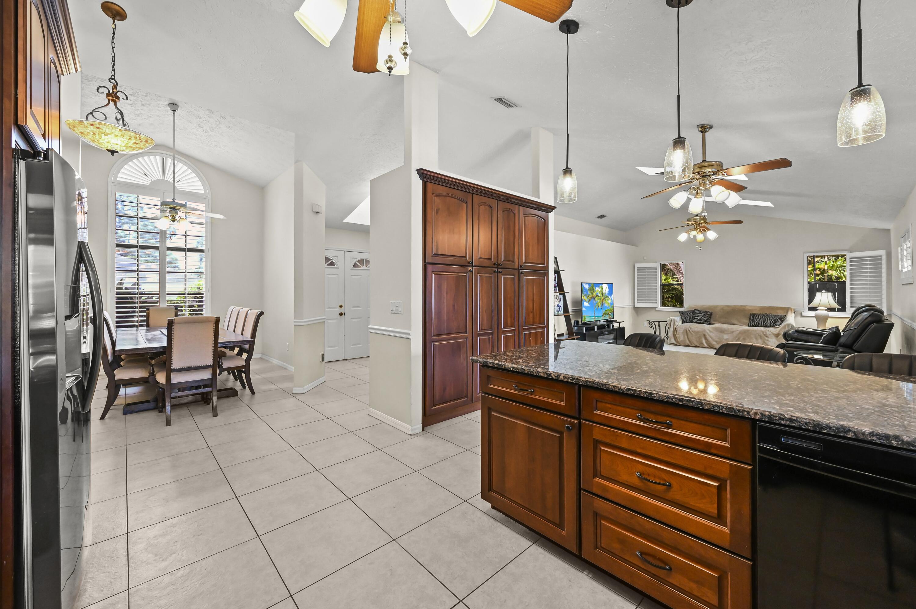 Open-plan kitchen and living area with a granite island, dark wood cabinets, and shuttered windows.