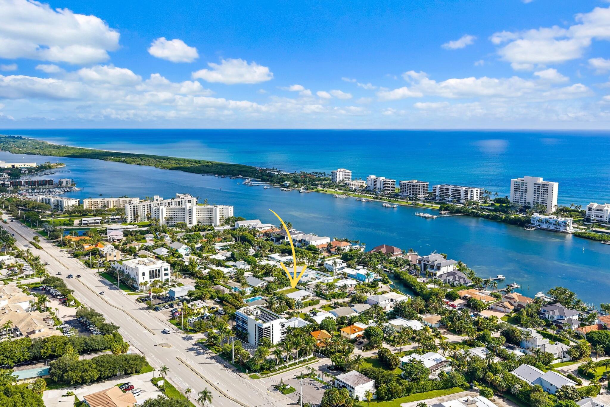Aerial view of a coastal neighborhood, with a yellow arrow marking a home beside the water.