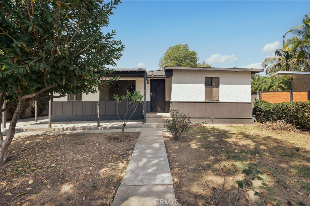 Single-story home with a covered porch and concrete walkway through a dry front yard.