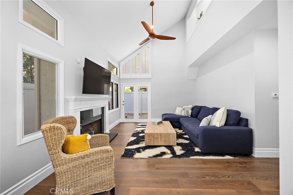 Living room with a vaulted ceiling, white fireplace, navy sectional, and wicker chair.