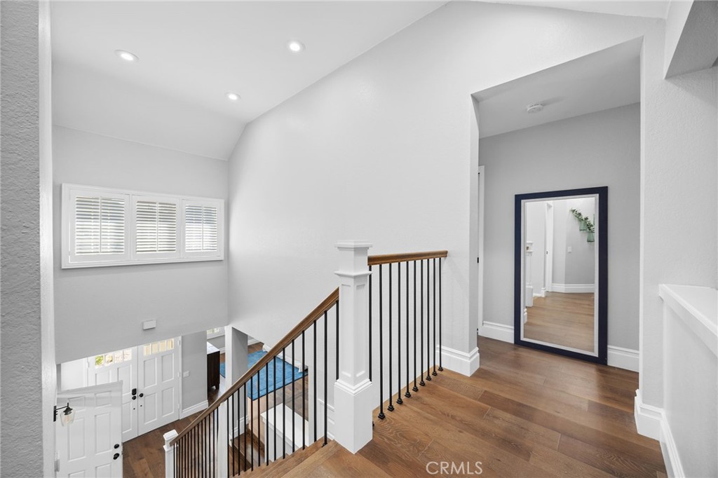 Upstairs landing overlooking a staircase with dark metal balusters and hardwood floors.