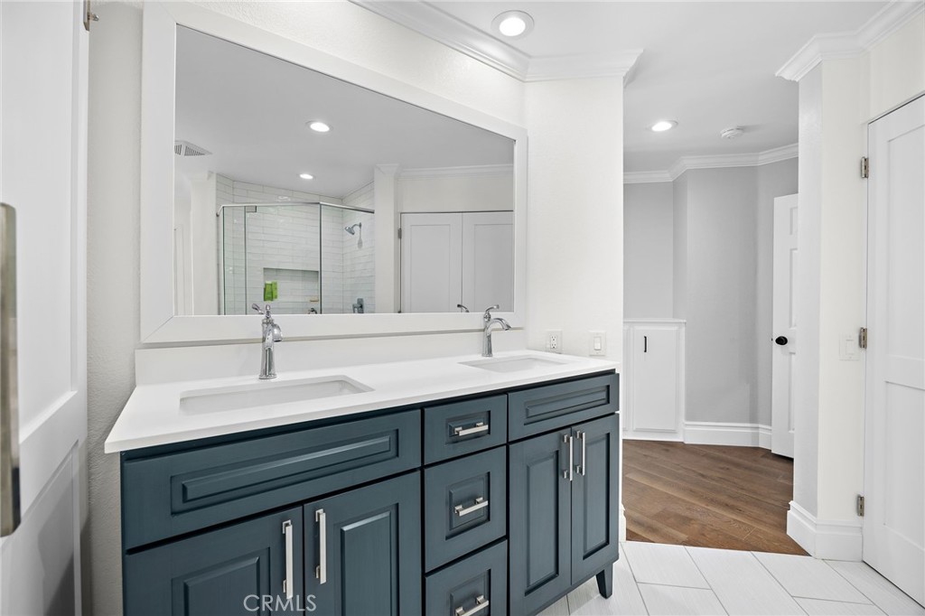 Bathroom with a dark blue double vanity, white countertop, and glass-enclosed tiled shower.