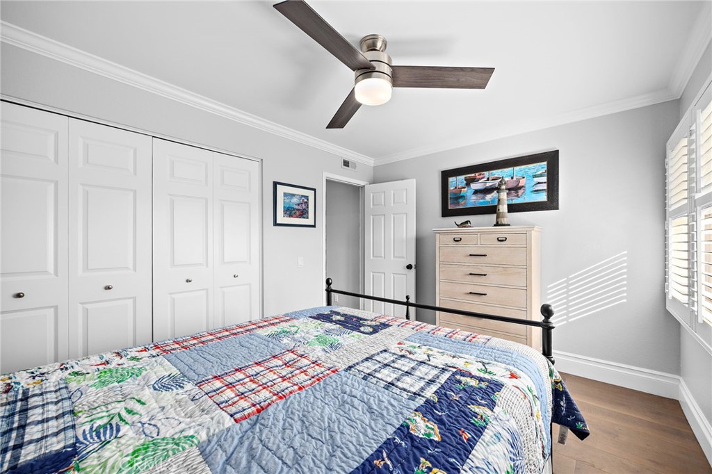 Bedroom with a colorful patchwork quilt, white paneled closets, and a light wood dresser.