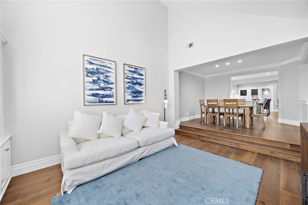 Living room with white sofa and blue rug opening to a raised dining area.