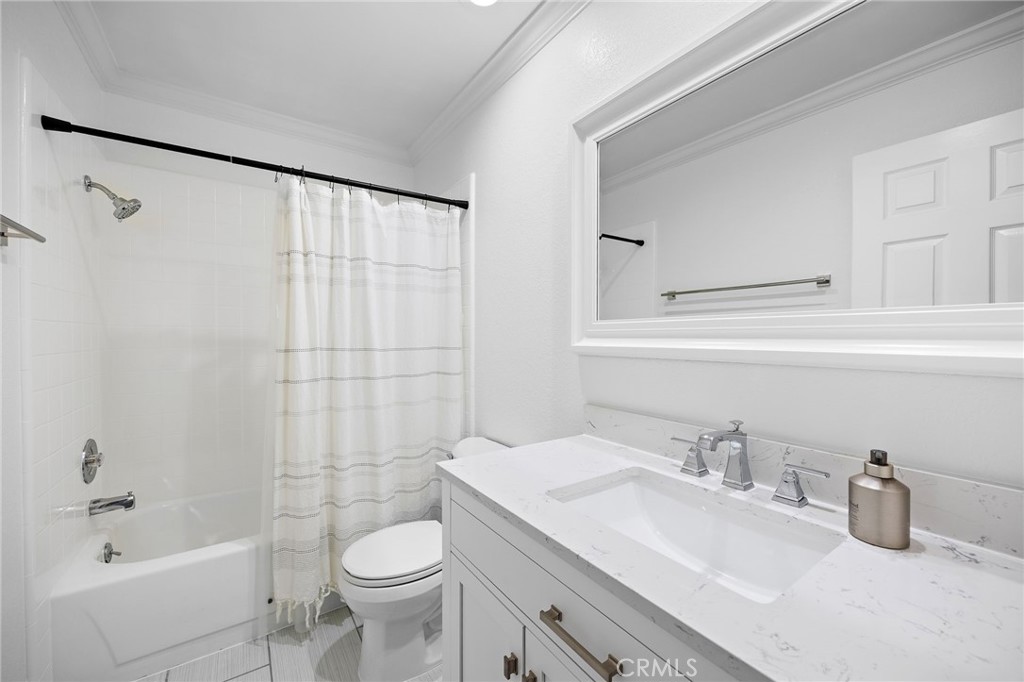 White bathroom with a tub-shower, striped curtain, and marble-look vanity countertop.