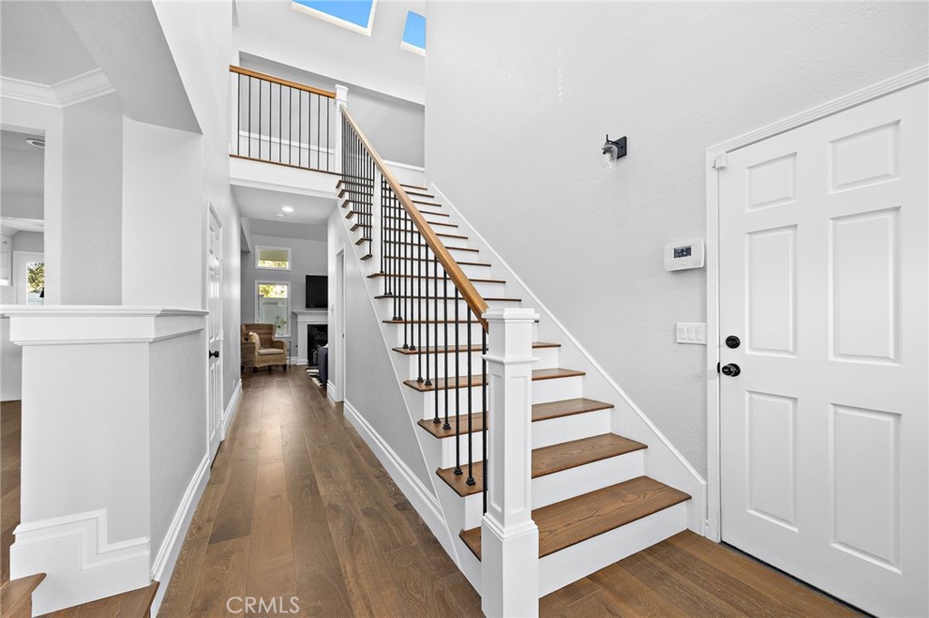Entry hall with wood floors and a staircase with dark balusters and a wood handrail.