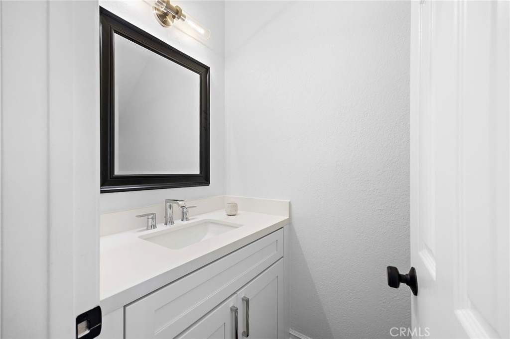 Bathroom vanity with a white countertop, chrome faucet, and large black-framed mirror.