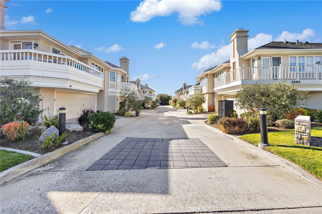 Attached homes with balconies and garages line a landscaped shared driveway.