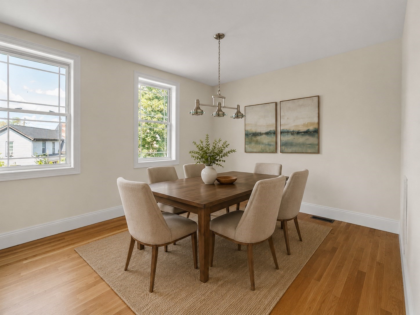 Dining room with a dark wood table, upholstered chairs, and large sunlit windows.