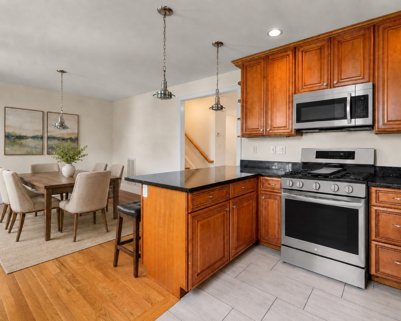 Kitchen with warm wood cabinets and stainless steel appliances beside a dining area.