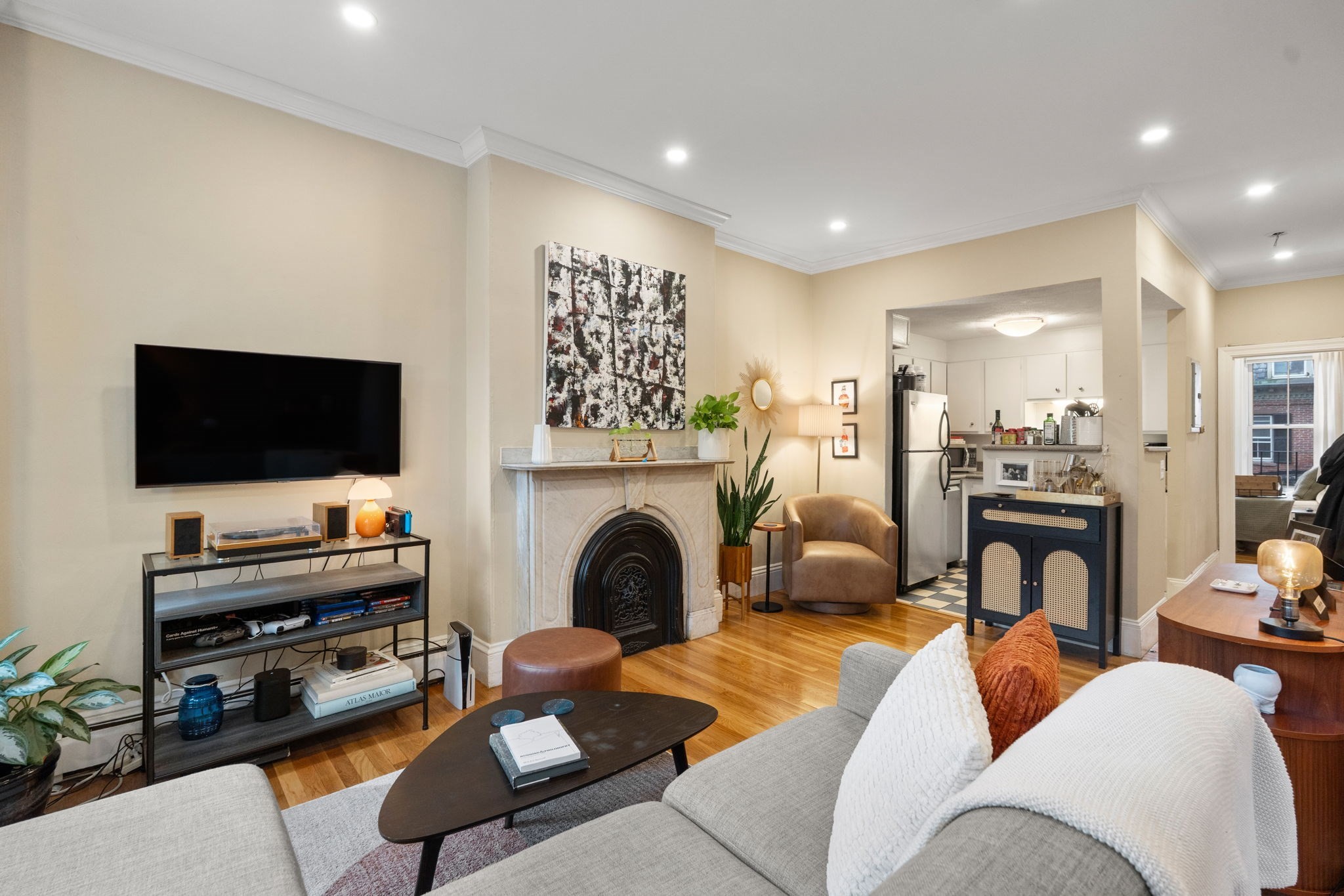 Furnished living room with a decorative fireplace, gray sectional, and open kitchen.