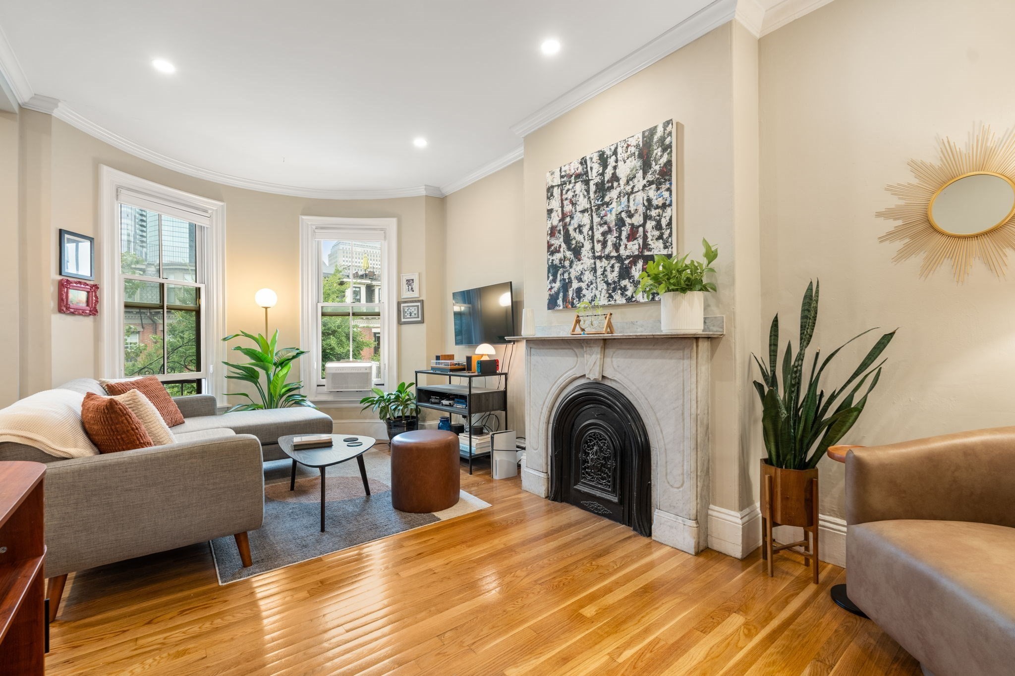 Living room with a marble fireplace, hardwood floors, and large windows.
