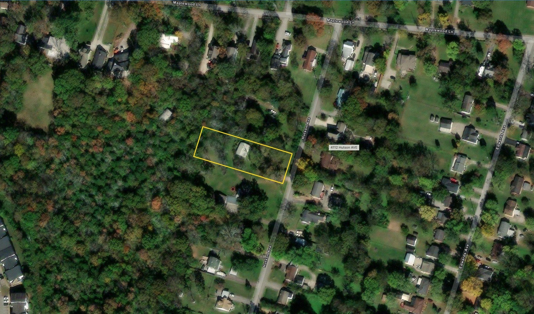 Aerial view of the wooded 4112 Hutson Avenue lot, outlined in yellow beside the street.