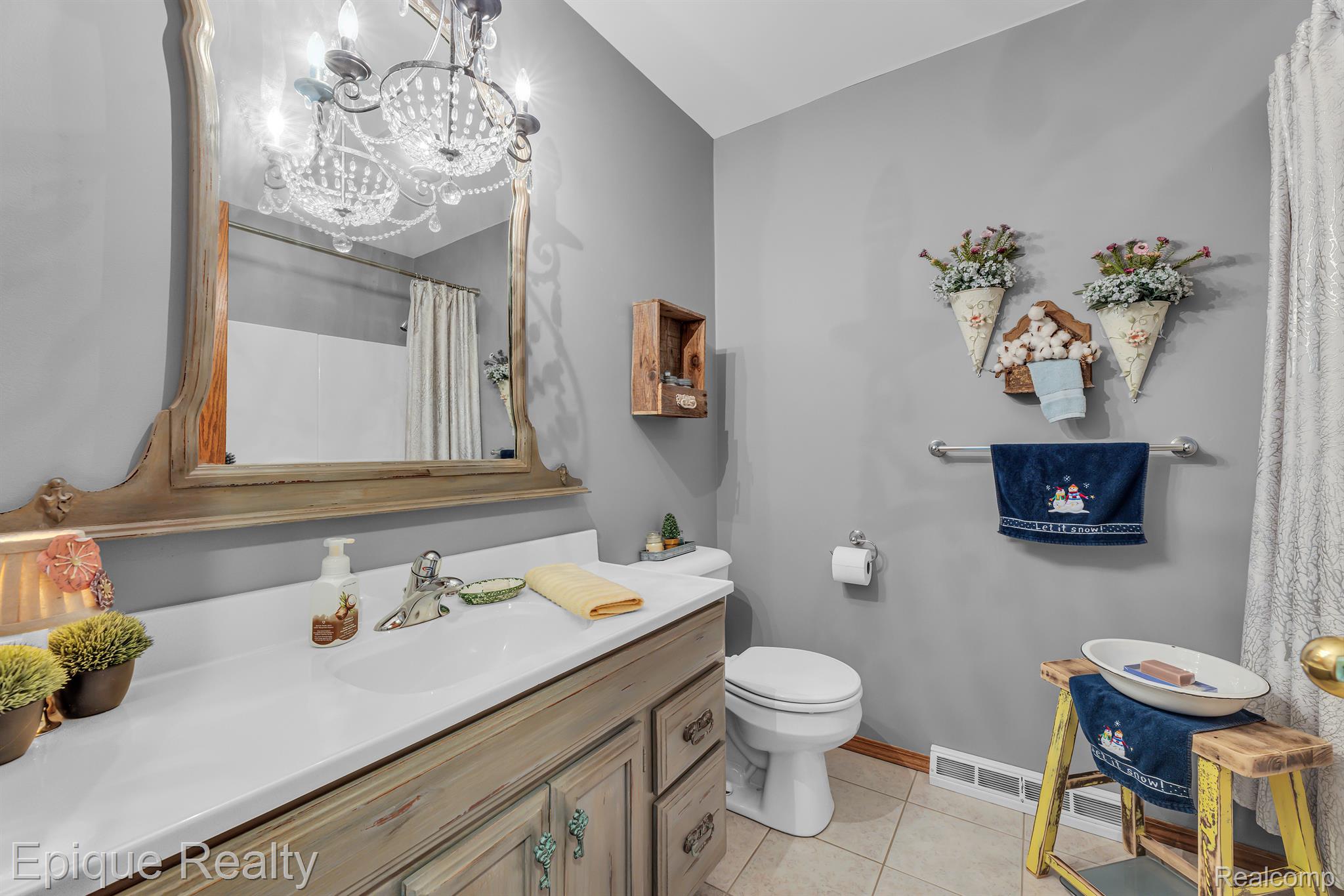 Bathroom with a weathered wood vanity, framed mirror, and blue holiday towel.
