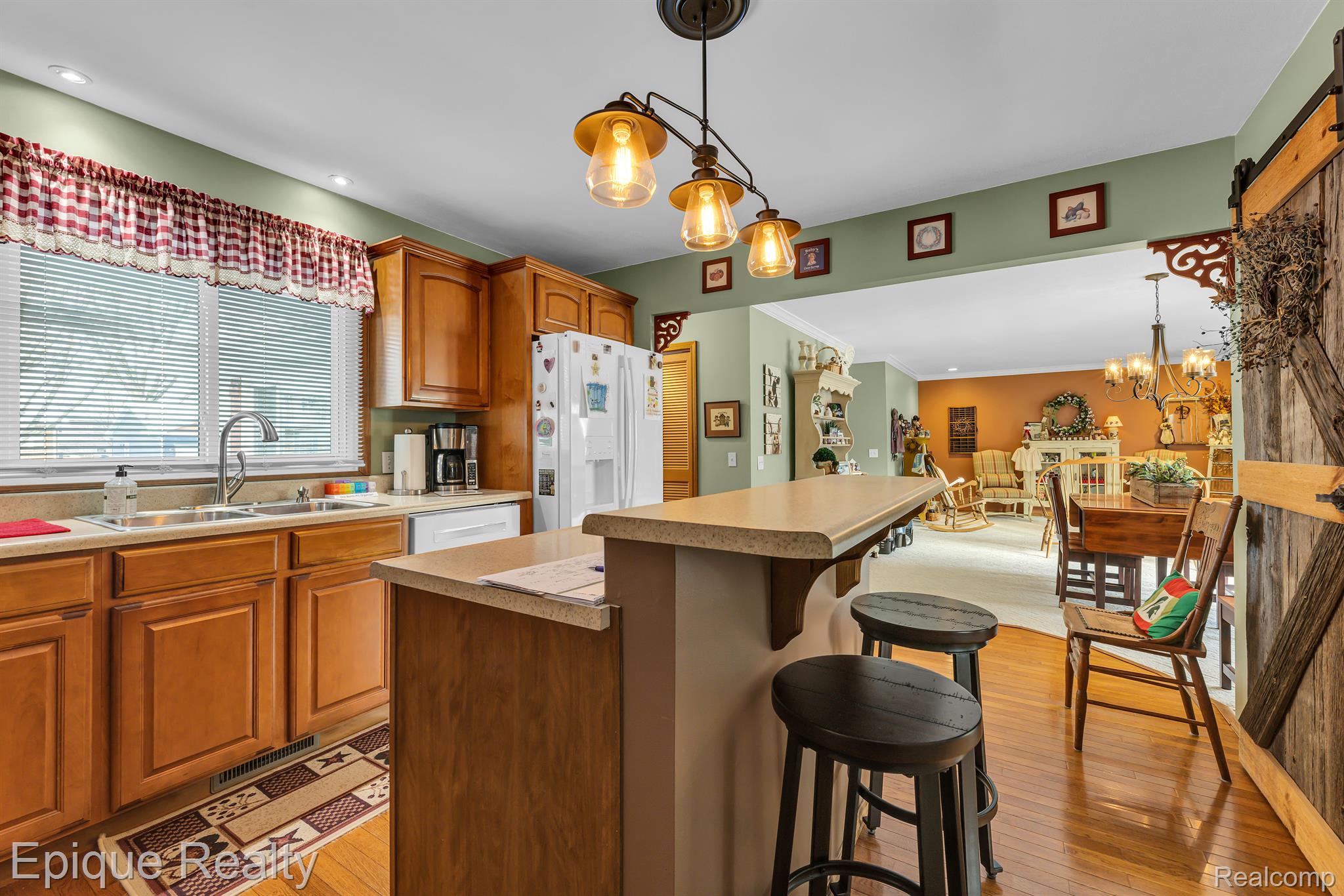 Kitchen with wood cabinets and a large breakfast peninsula opening onto a dining and sitting area.