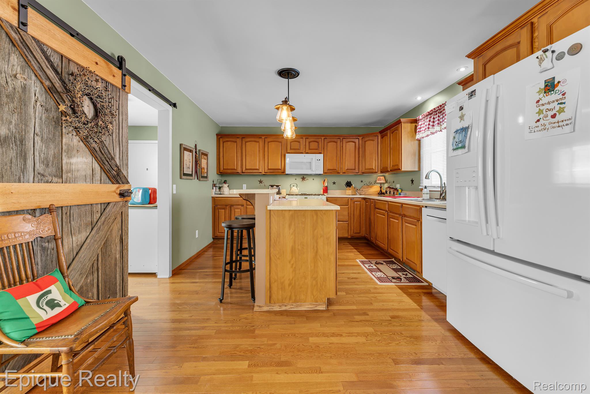 Kitchen with warm wood cabinetry, central island, hardwood floors, and a rustic sliding barn door.