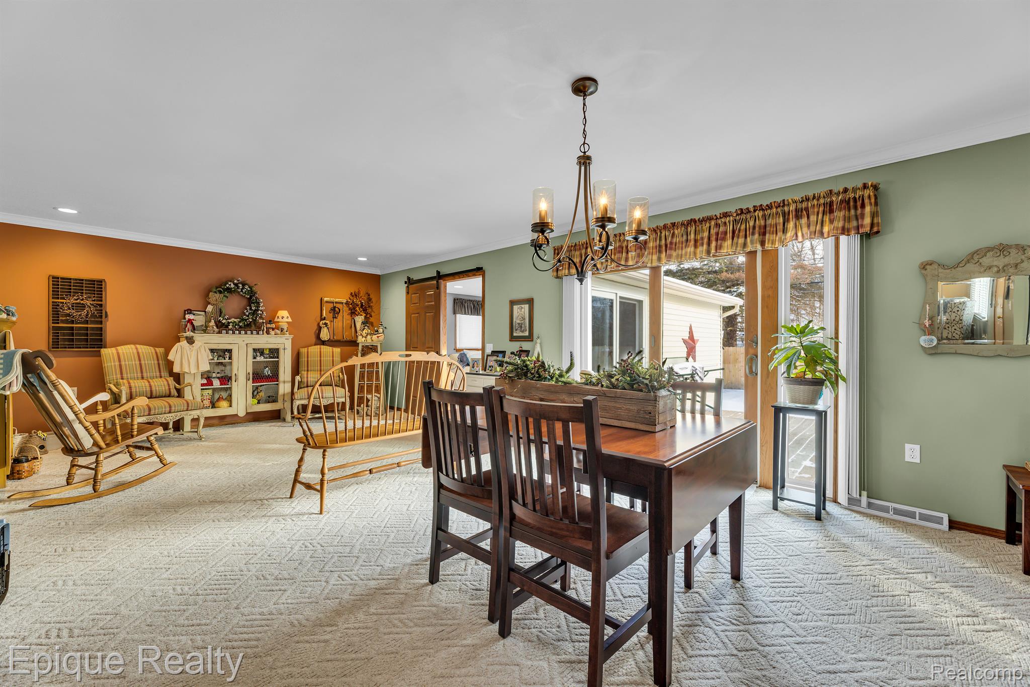 Dining and living area with a dark wood table, patterned carpet, and sliding glass doors.