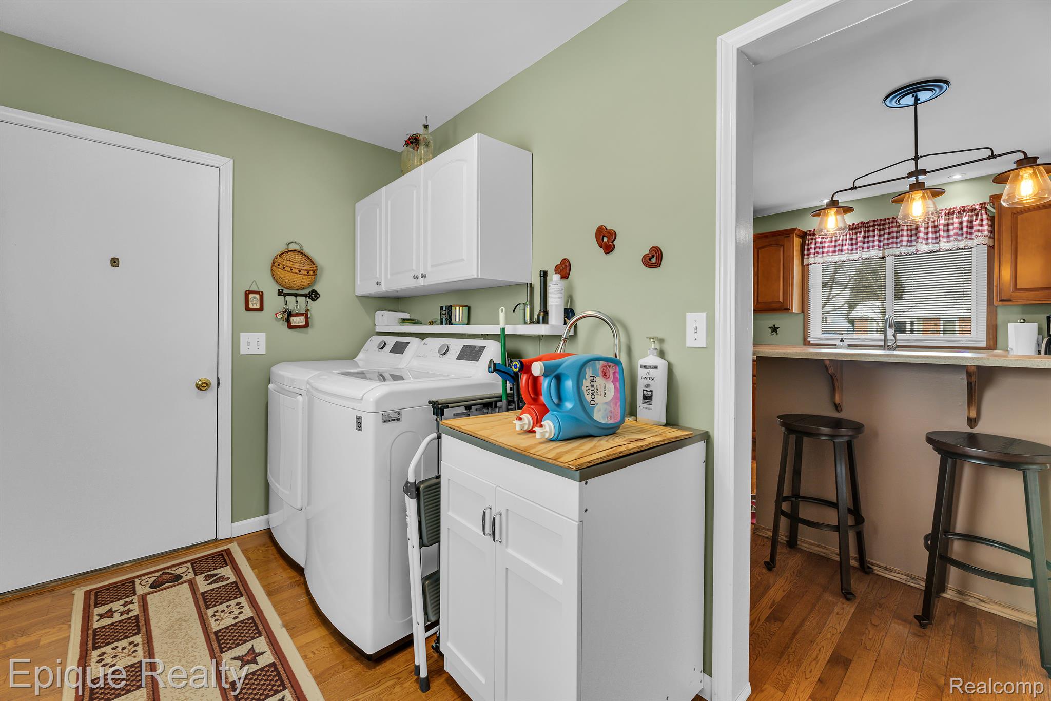 Laundry room with white washer and dryer, overhead cabinets, and a wood-topped folding counter.