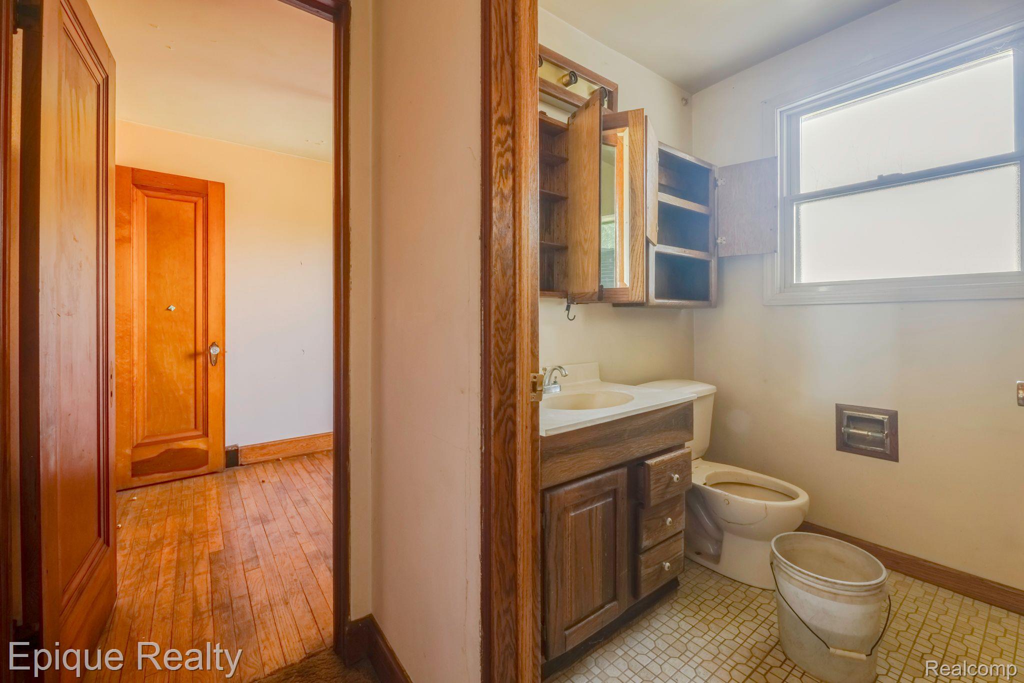 Bathroom with a wood vanity and medicine cabinet, toilet, and bright window.