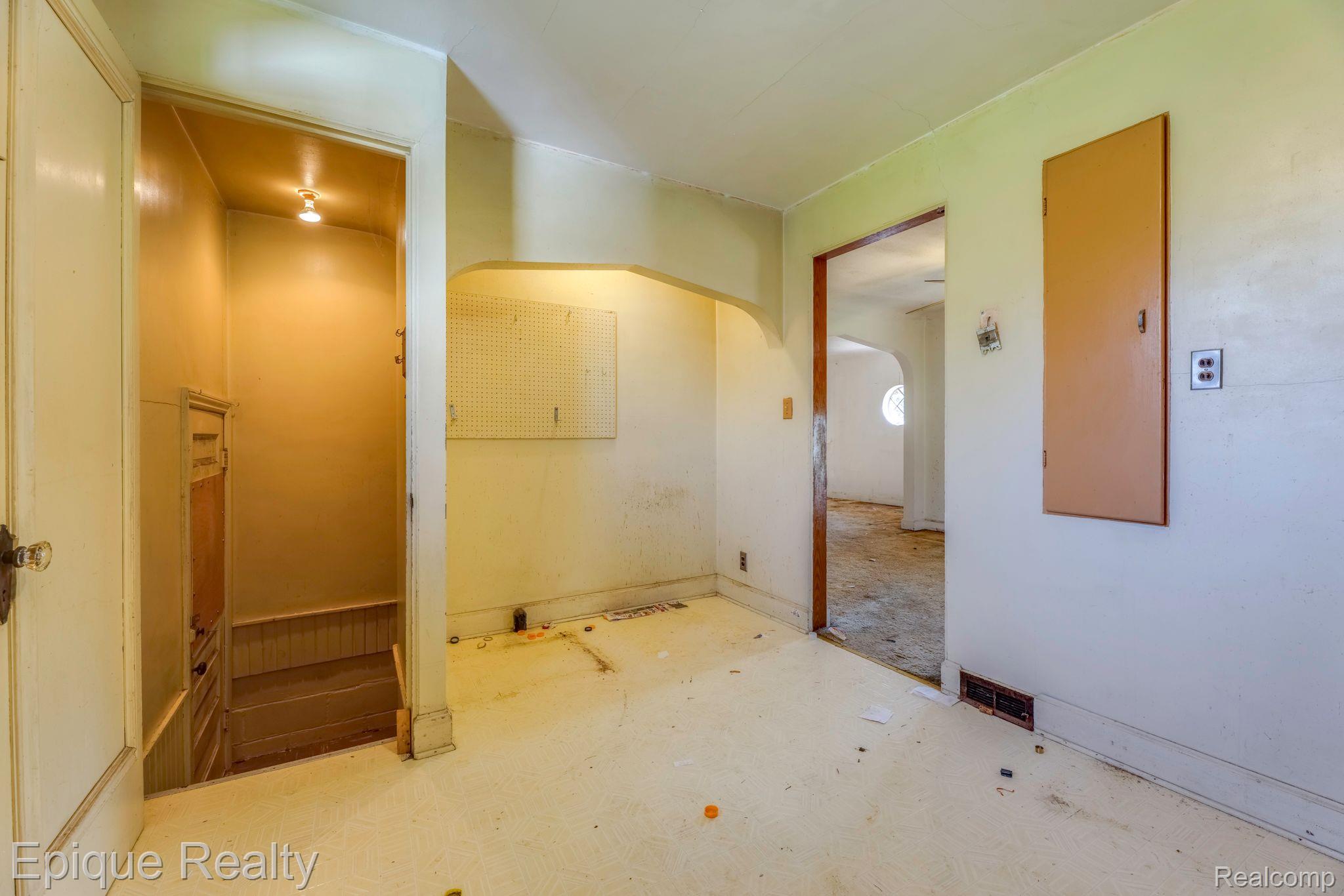 Vacant interior room with a pegboard, large electrical panel, and open stairwell.