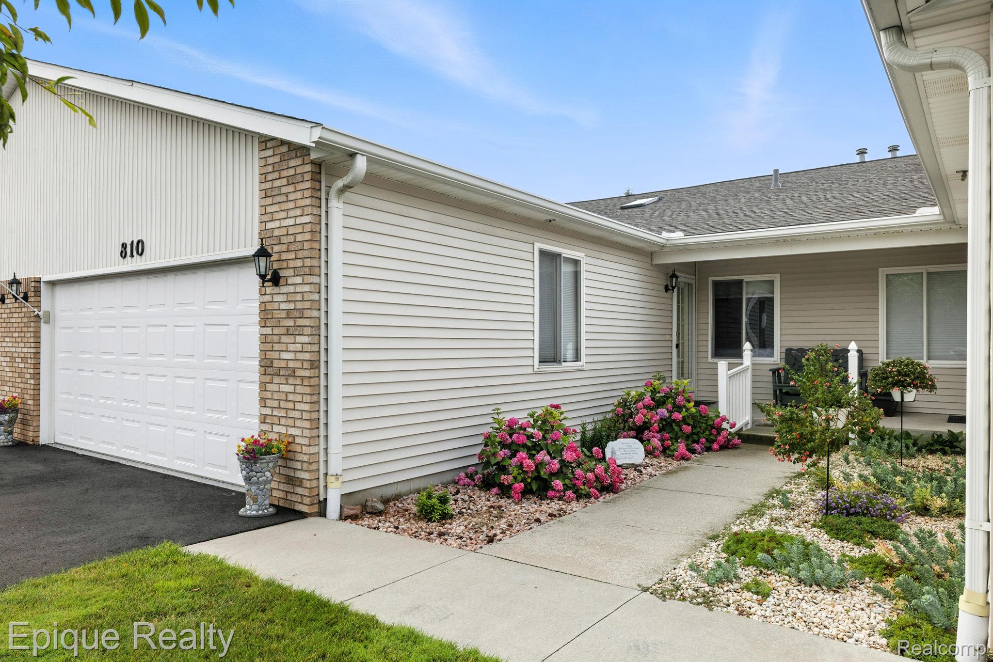 Home exterior with white garage, covered entry, and flower beds along the walkway.