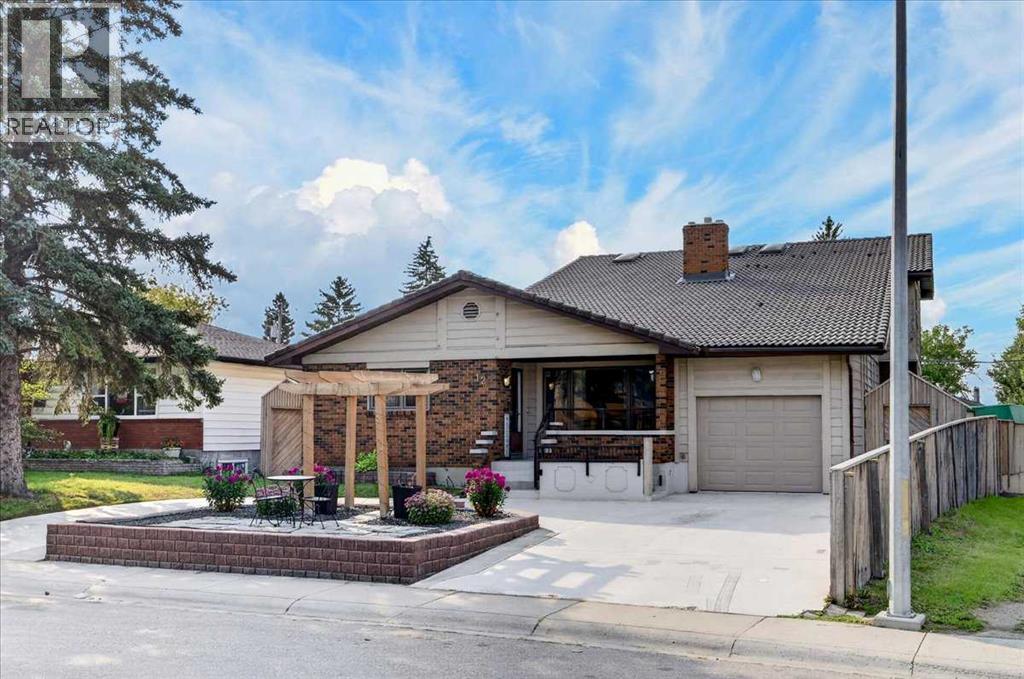 Single-story brick house with an attached garage, raised patio, wooden pergola, and broad driveway.