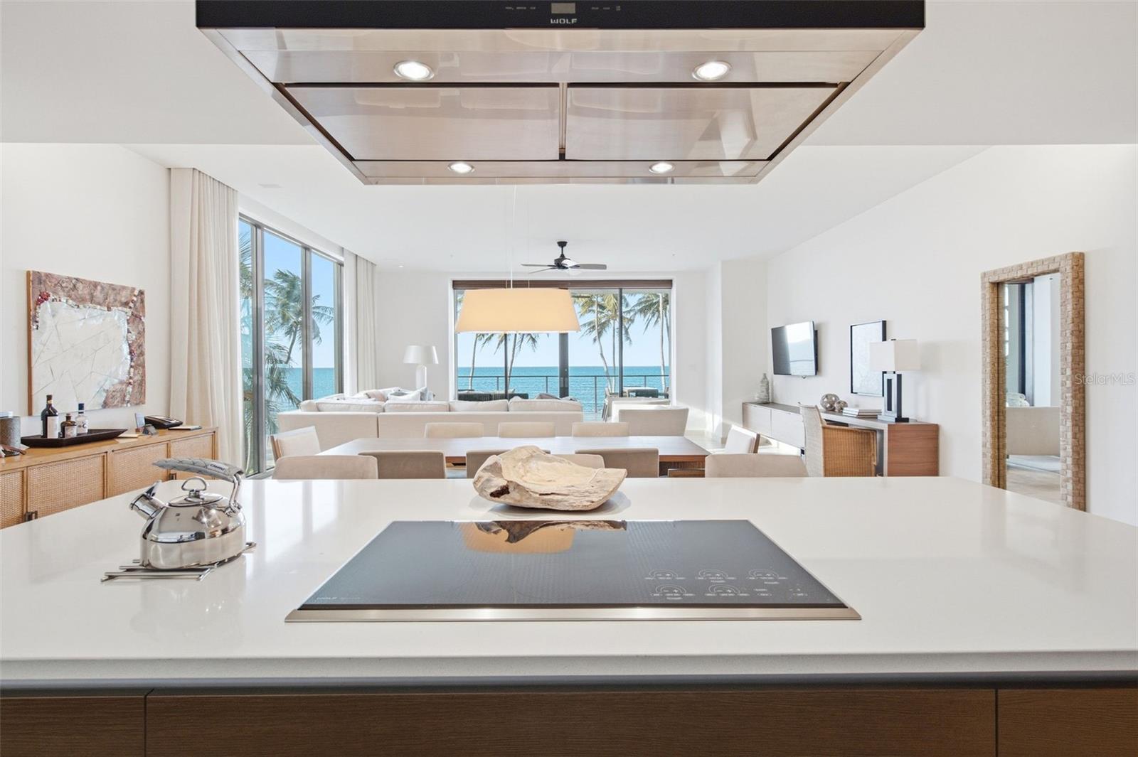Open-plan kitchen and living area with an island, floor-to-ceiling windows, and ocean views.