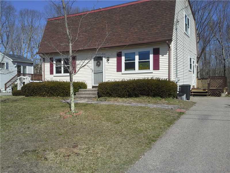 White-sided house with burgundy shutters, a steep brown roof, front lawn, and paved driveway.