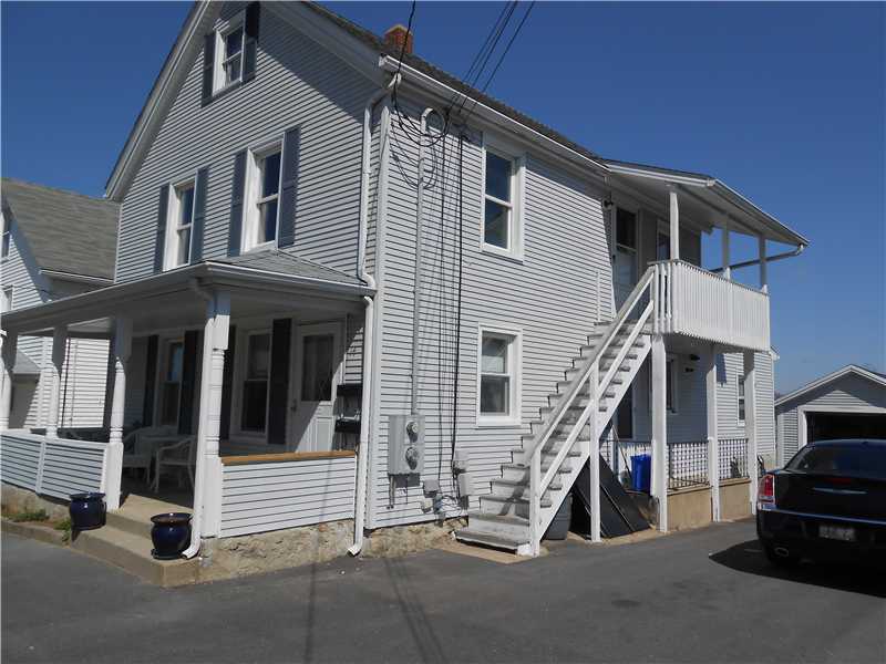 Two-story gray house with covered porches and an exterior staircase to the upper-level entrance.