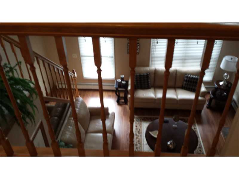 Living room with cream sofas and hardwood floors, seen through a wooden staircase railing.