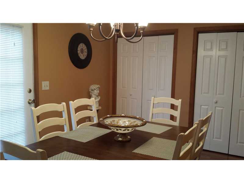 Dining room with a dark wood table, light chairs, patterned placemats, and a chandelier.