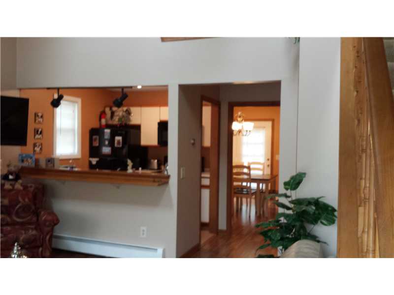 Living room with a leather armchair, kitchen pass-through, and doorway to a hardwood dining area.