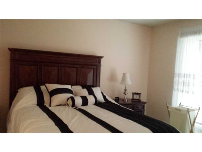 Bedroom with a dark wood bed, black-and-white bedding, and a bright curtained window.