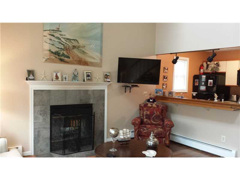 Living room with a stone fireplace, mounted television, and kitchen pass-through bar.