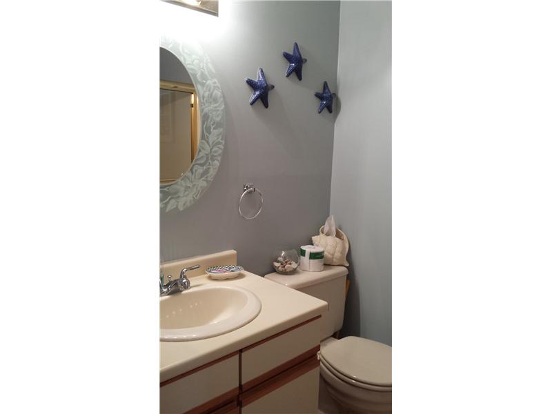 Bathroom with a cream vanity and sink, toilet, and blue starfish wall decorations.