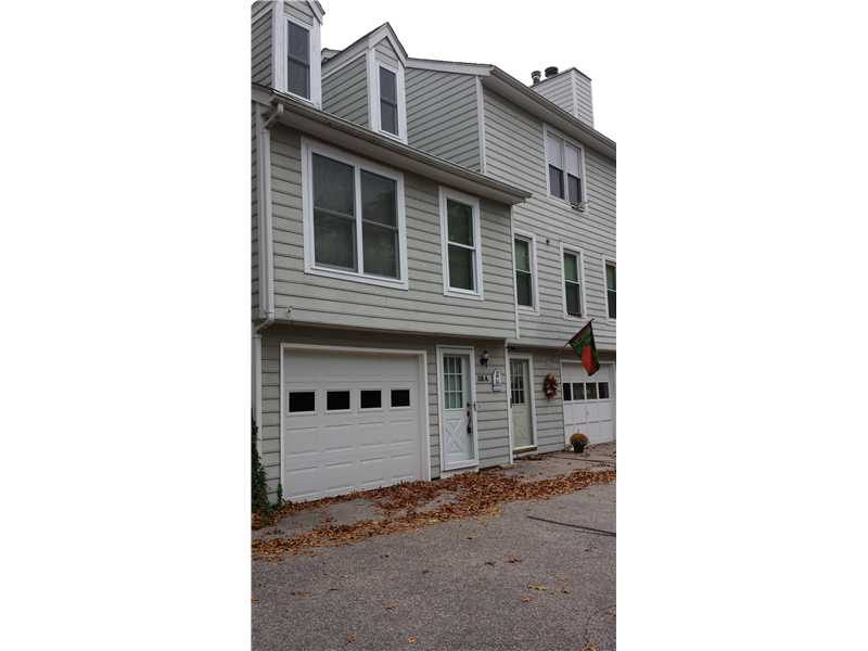 Gray multi-story townhouse with white trim, two garage doors, and a flag by the entrance.
