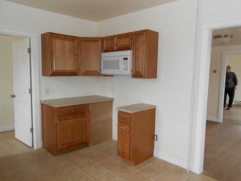 Kitchenette with wood cabinets, a built-in microwave, and a separate narrow counter.