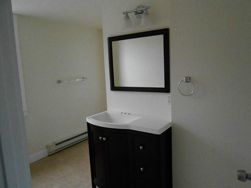 Bathroom with a dark vanity, white sink, and large black-framed mirror.
