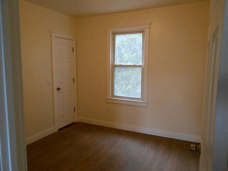 Empty room with wood flooring and a white-trimmed window.