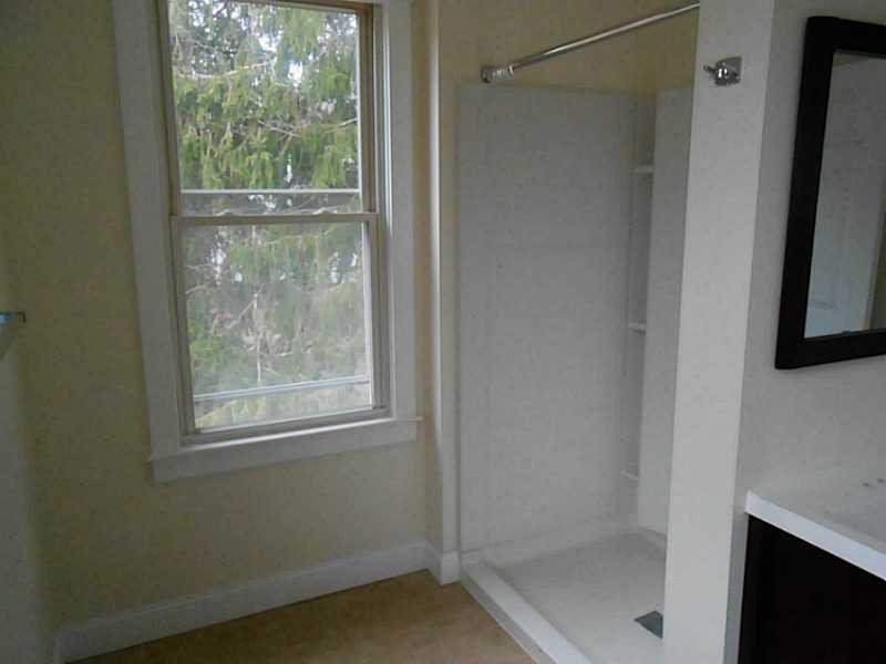 Bathroom with a white walk-in shower, built-in shelves, and a window.