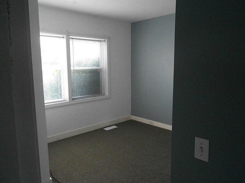 Empty carpeted bedroom with two windows and a blue-gray accent wall.