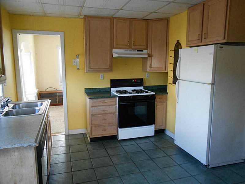 Kitchen with wood cabinets, green countertops, white appliances, and dark tile flooring.