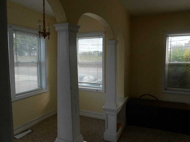 Interior room with arched openings, white columns, and windows with blinds.