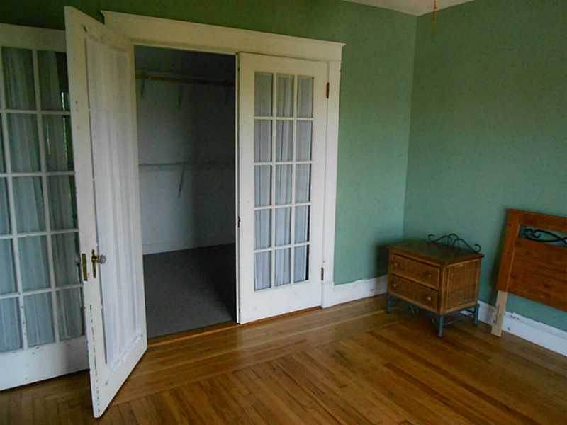 Bedroom with green walls, hardwood floors, and open French doors.