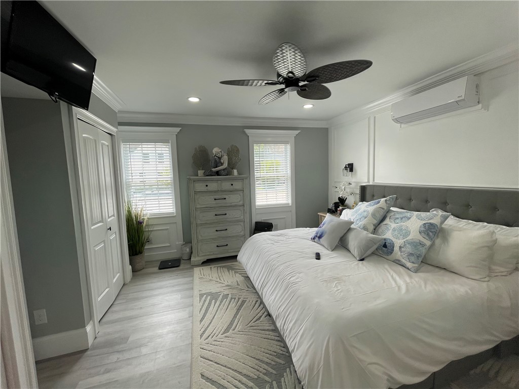 Furnished bedroom with a large white bed, gray walls, ceiling fan, and two windows.