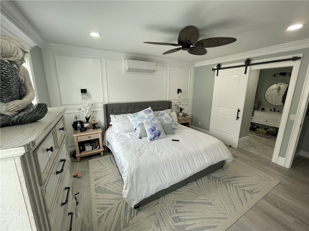 Bedroom with a white bed, paneled walls, patterned rug, and barn door to the bathroom.