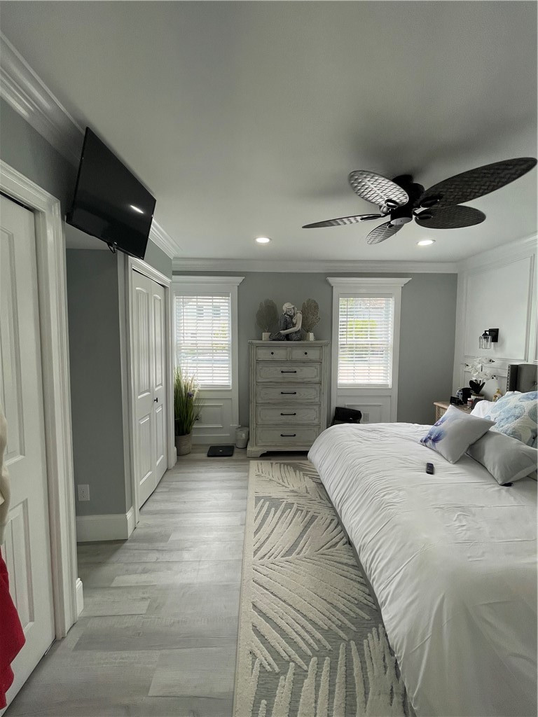 Bedroom with a white bed, patterned rug, tall chest of drawers, and ceiling fan.