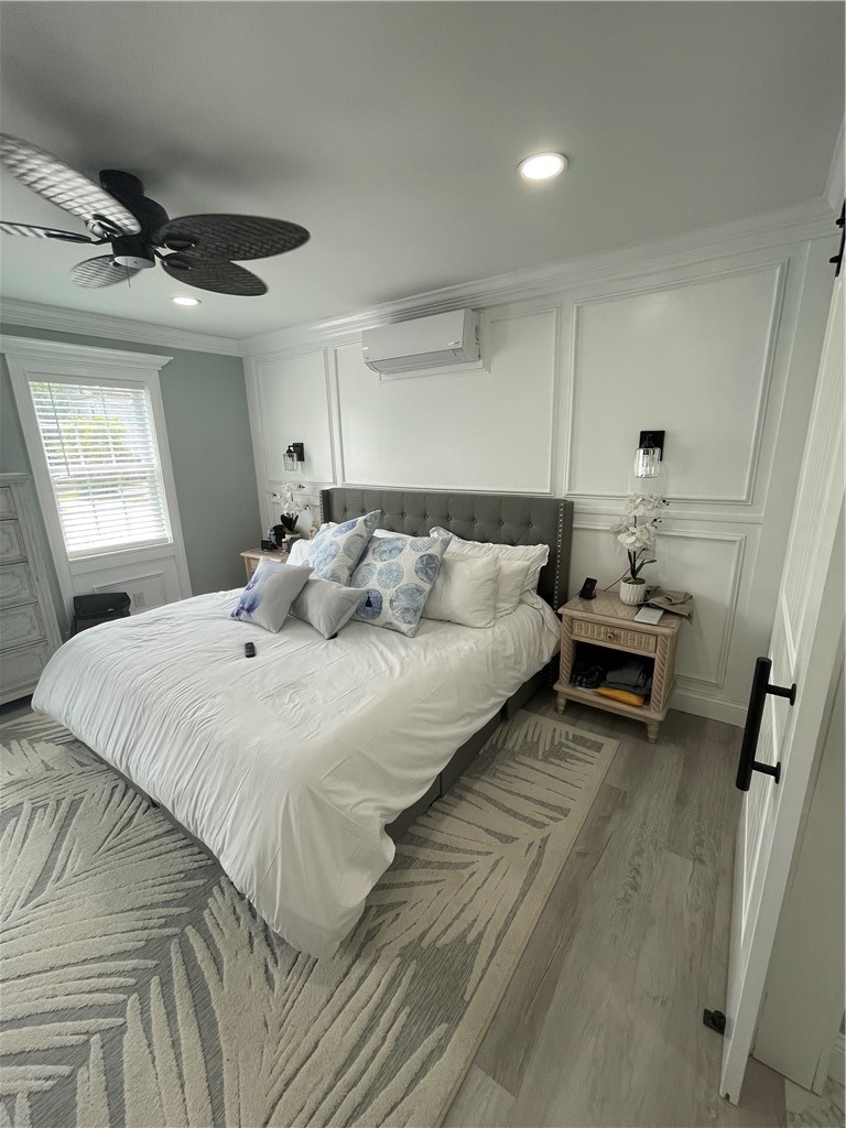 Bedroom with a white bed, tufted gray headboard, paneled walls, and a ceiling fan.